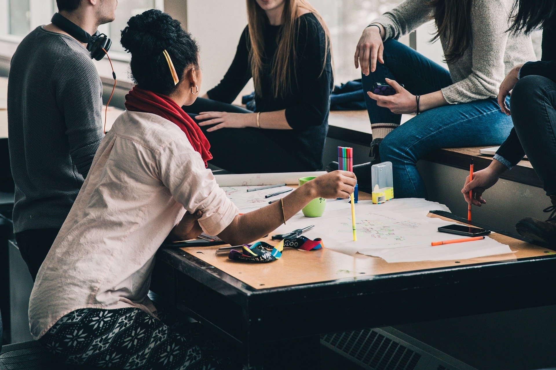 Studierende sitzen um einen Tisch herum und diskutieren