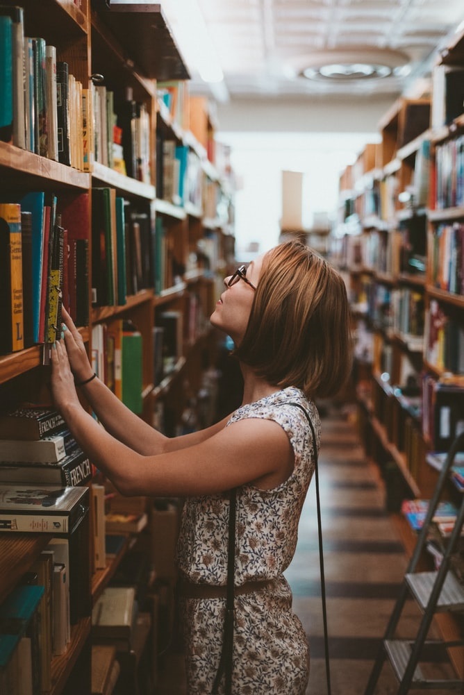 Eine Frau sucht nach einem Buch in einer Bibliothek