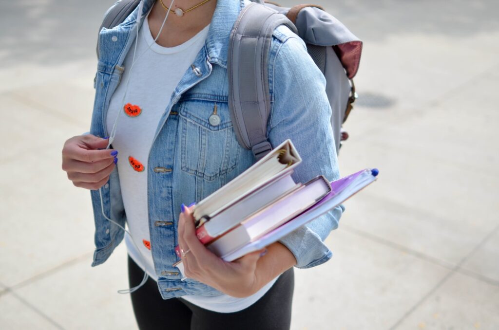 eine weibliche Person mit Büchern unterm Arm