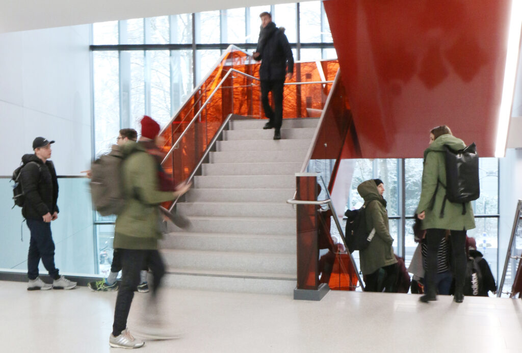 Mehrere Studierende mit und ohne Beeinträchtigung gehen eine Treppe in der deutschen Sporthochschule Köln hinauf oder herunter