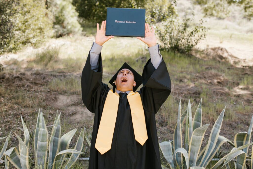 Student mit Doktorhut hält sein "Diploma of Graduation" hoch